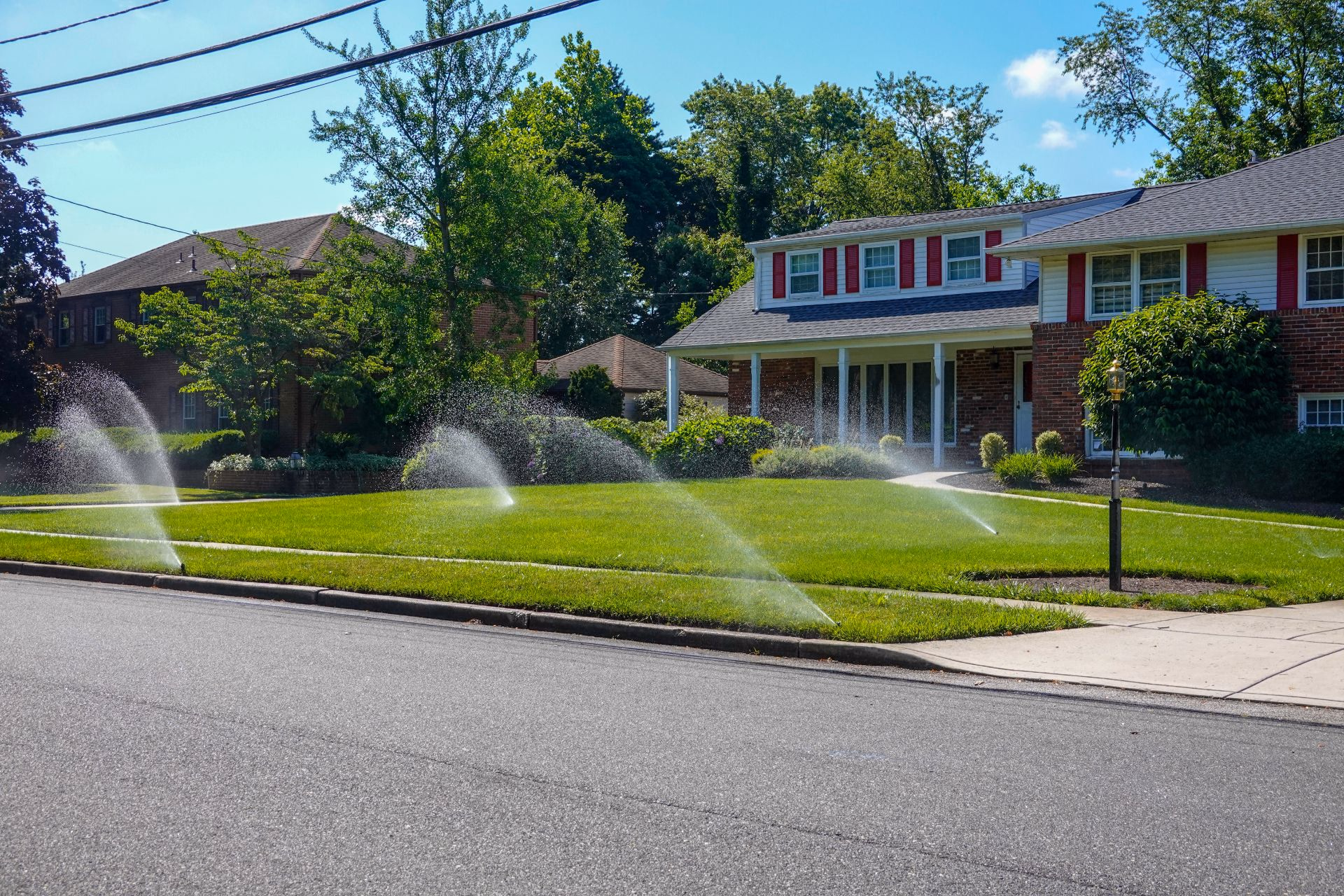 Sprinklers watering the front lawn of a suburban home
